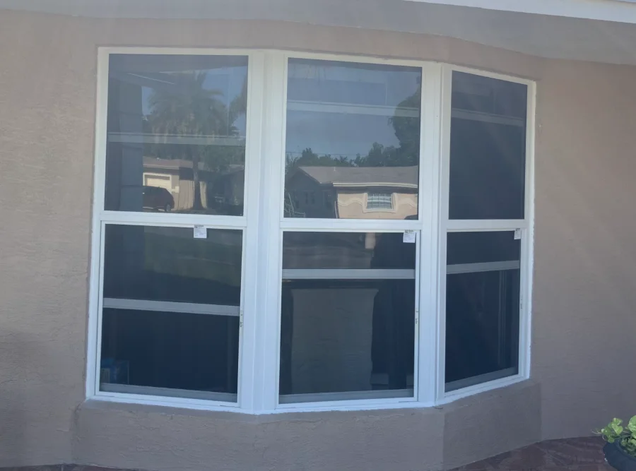 Three-panel impact bay window projecting from a South Florida home, white frames with tinted glass
