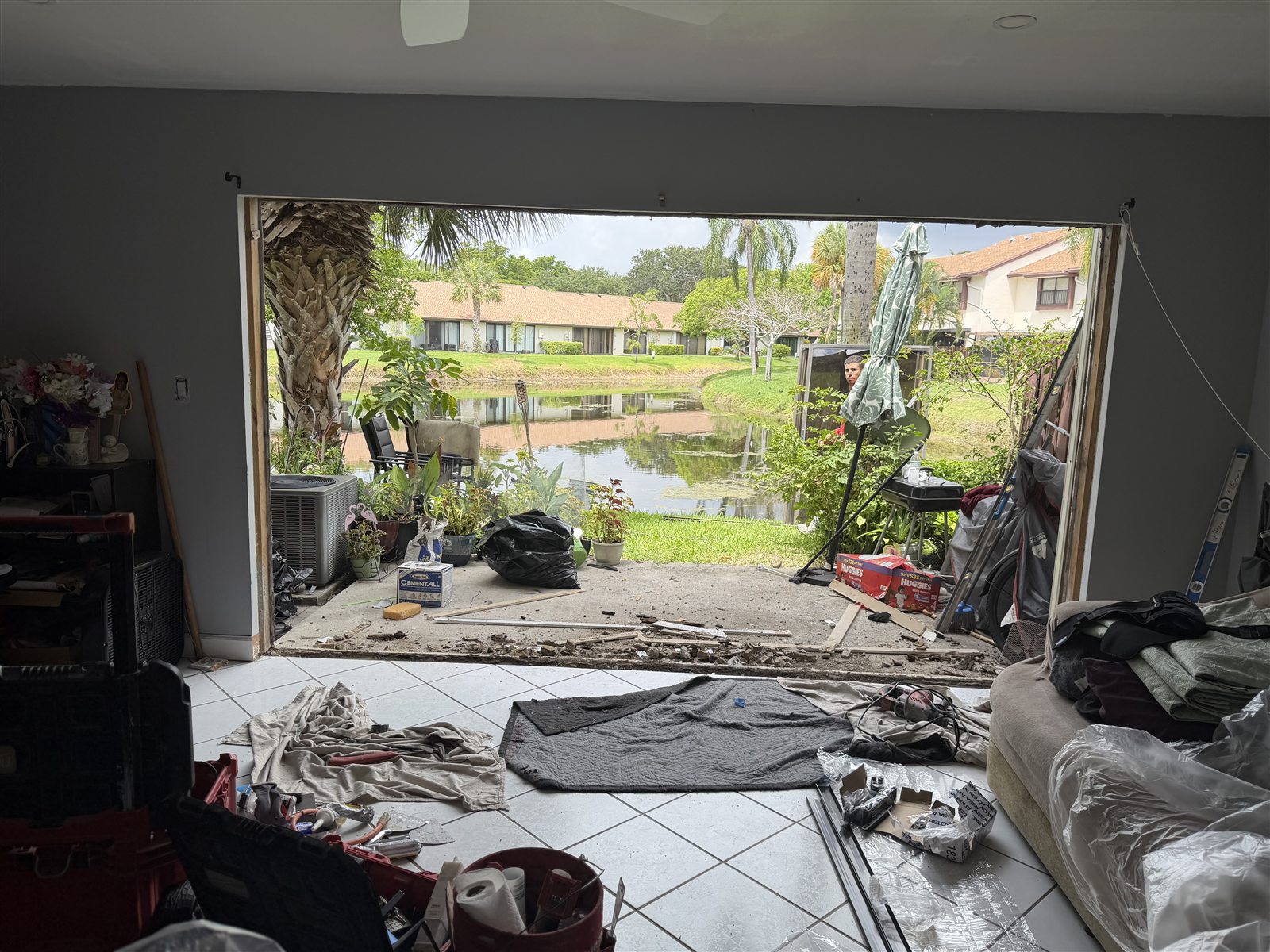 Rear opening in a Coconut Creek home stripped back to the block after the original sliding glass door was removed, looking out across the lake