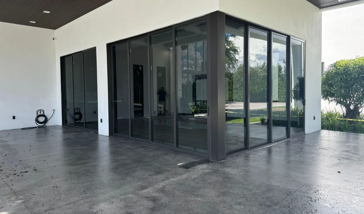 Dark-framed impact sliding doors wrapping the corner of a covered terrace